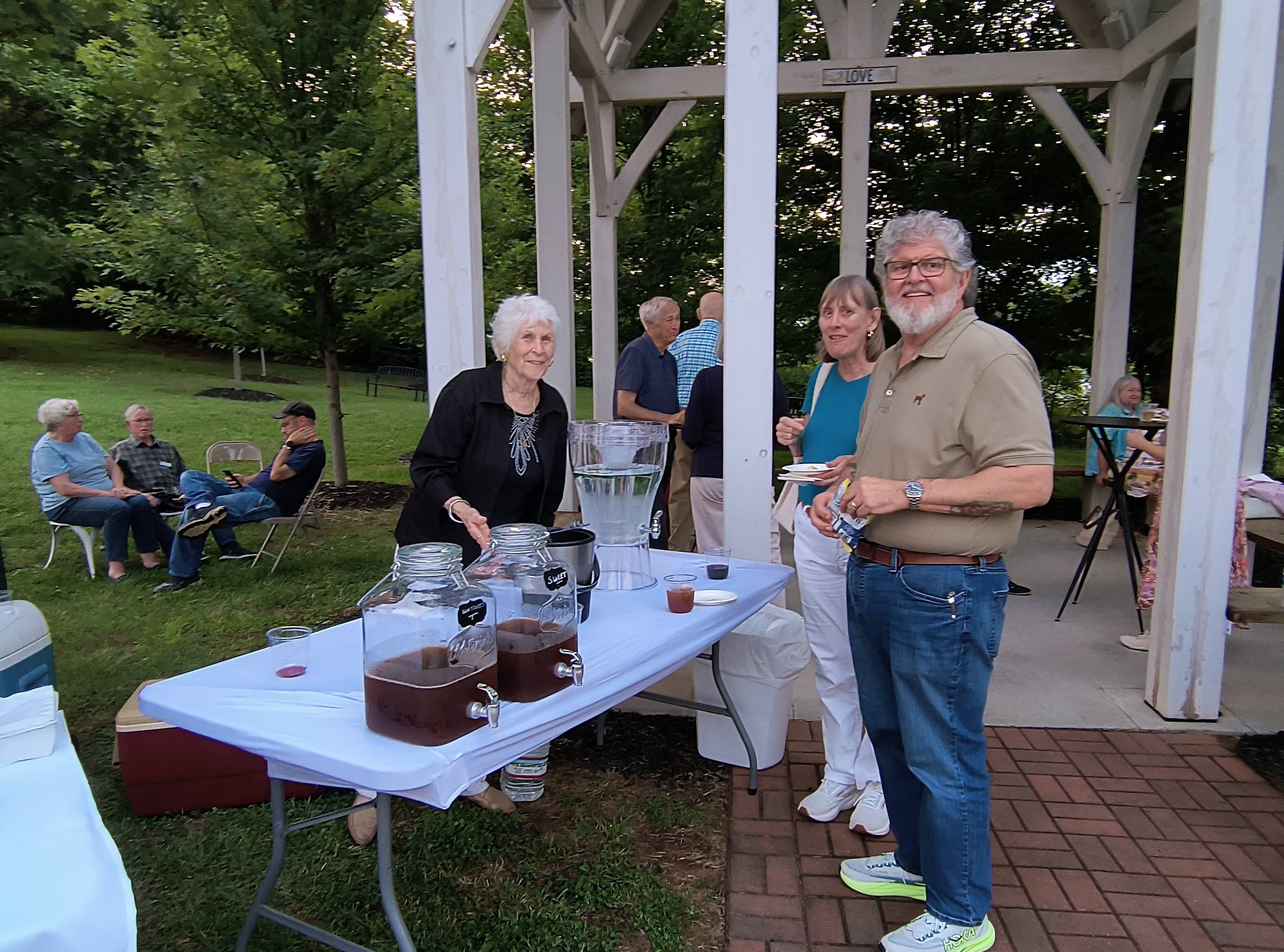 Guests gathered at the sweet tea and beverage table under the Arbor pergola