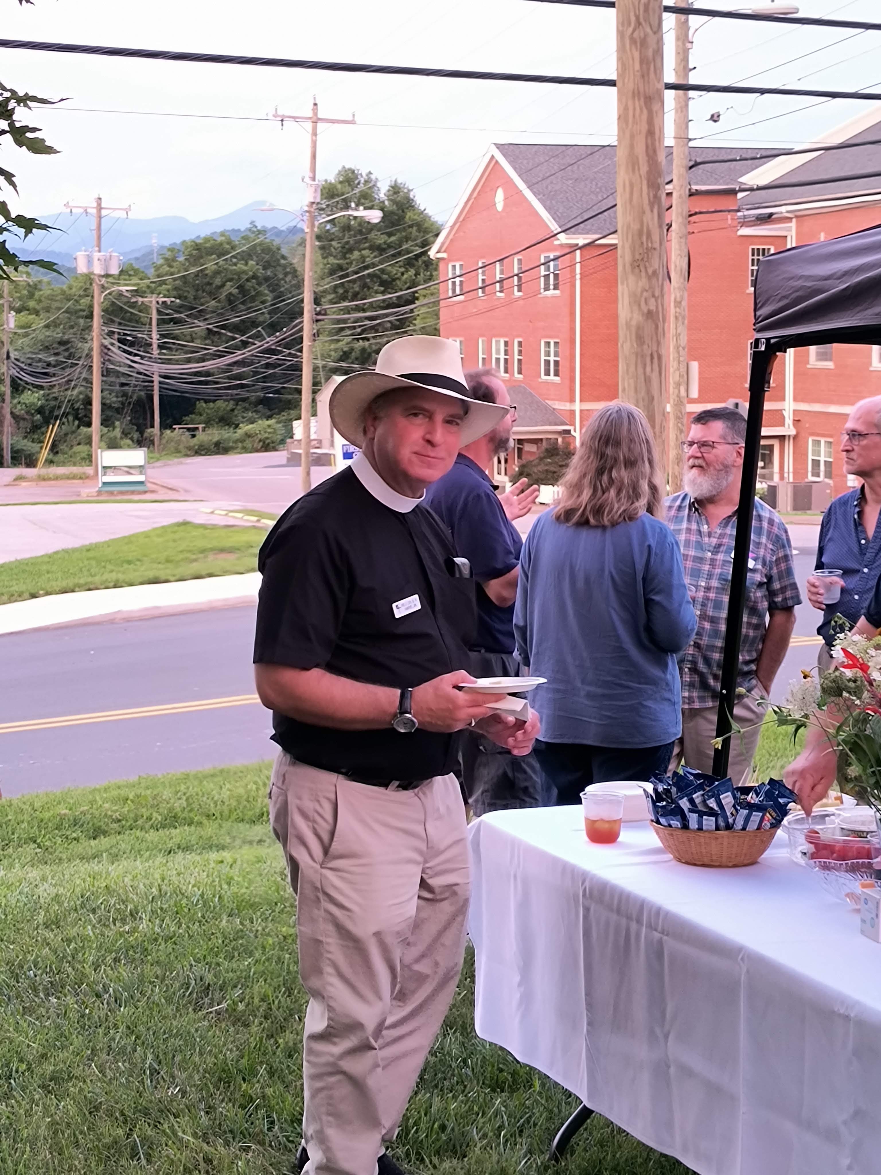 A member of the clergy holding a plate at the reception with the mountains behind