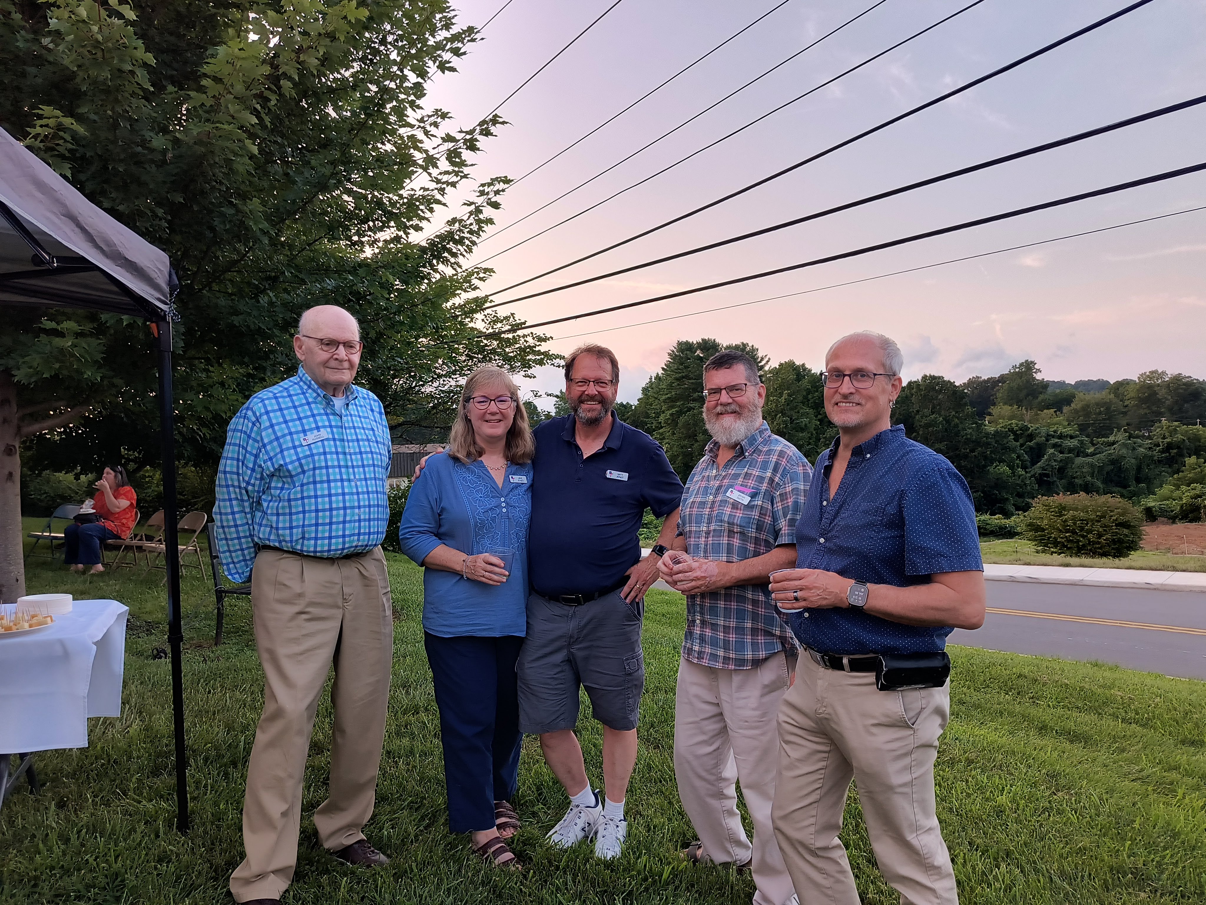 A group of five members posing together on the lawn at sunset