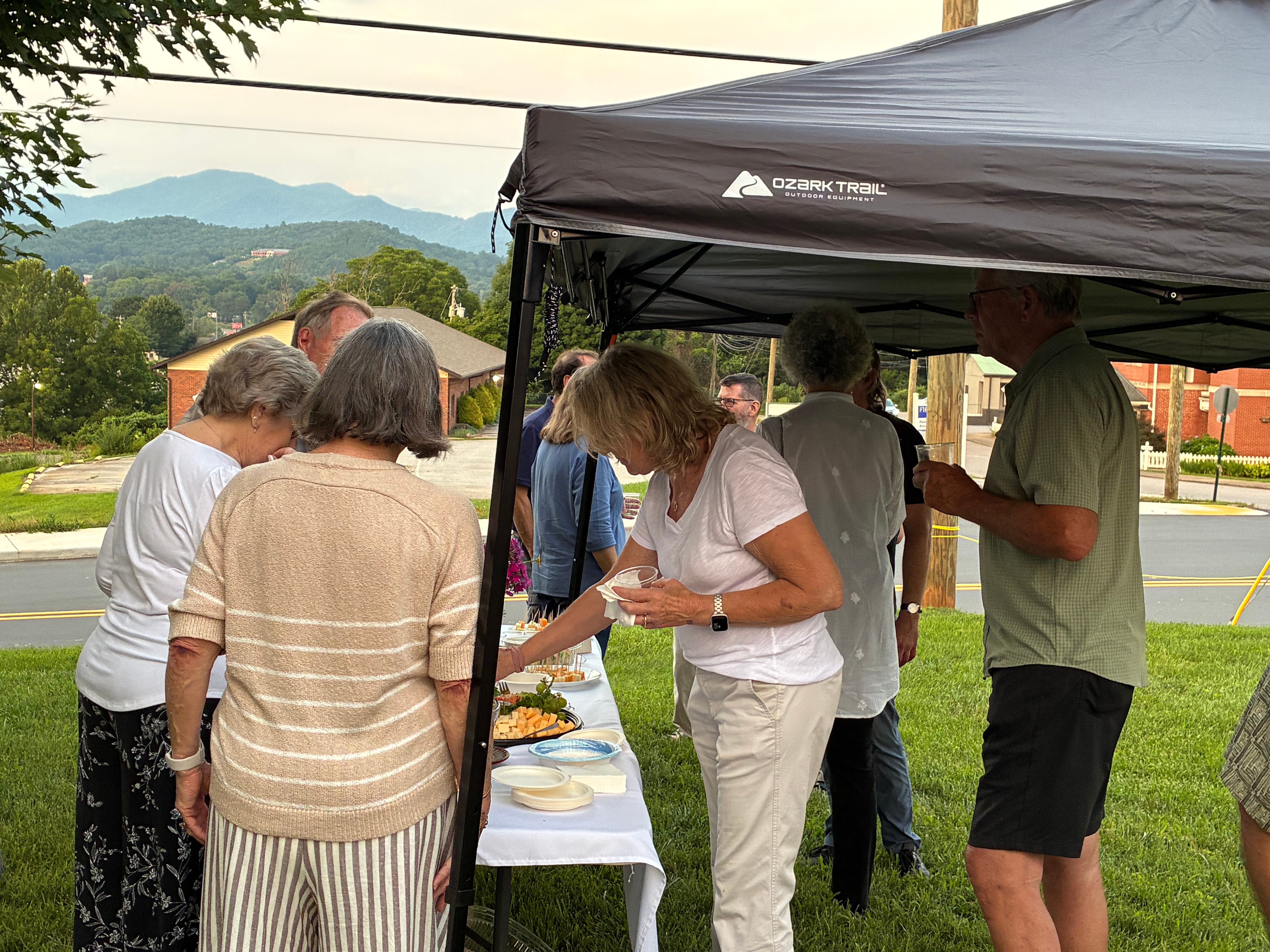 Guests at the refreshment table under the tent with the Blue Ridge mountains in the distance