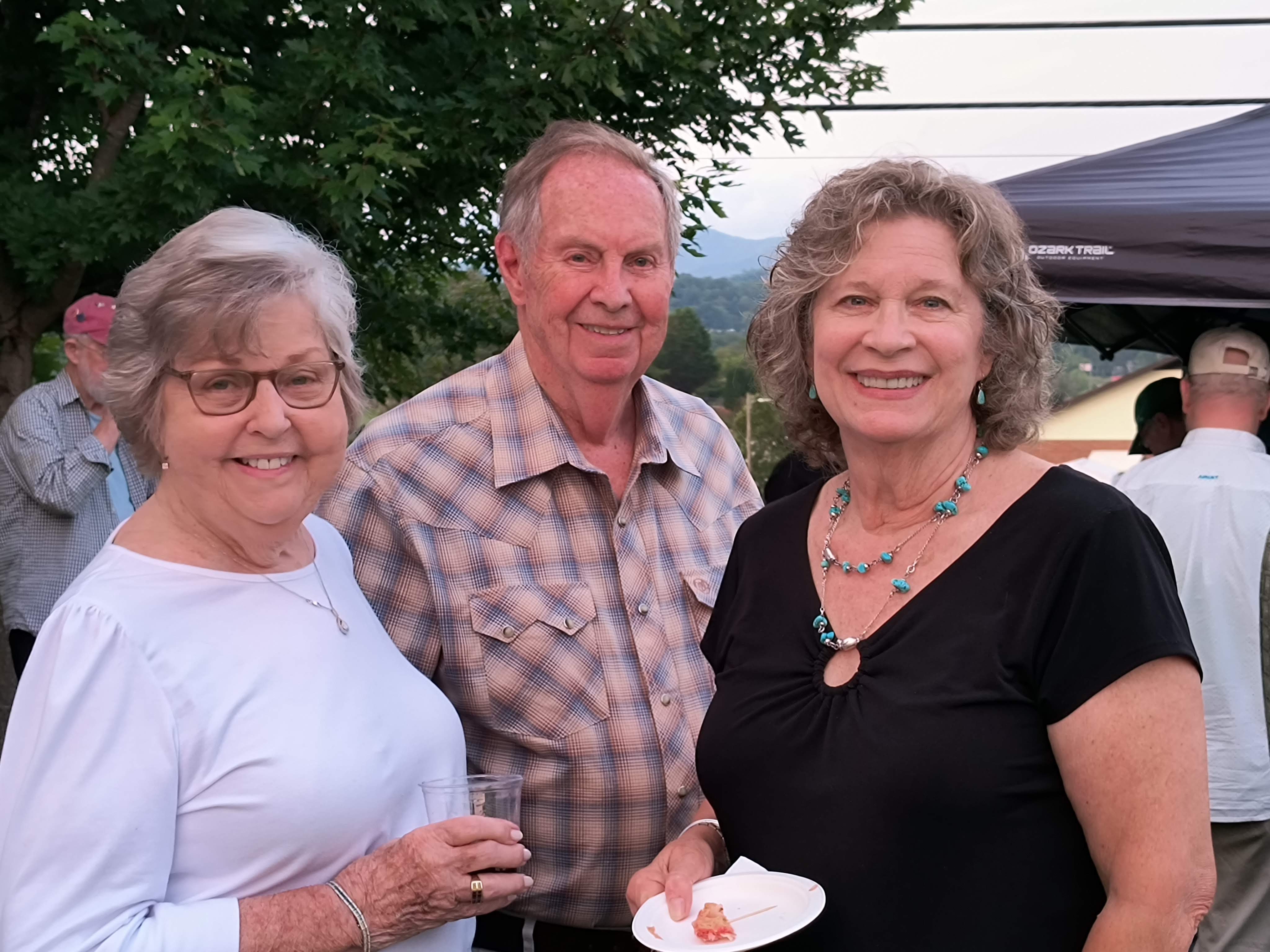 Three guests smiling together at the outdoor reception