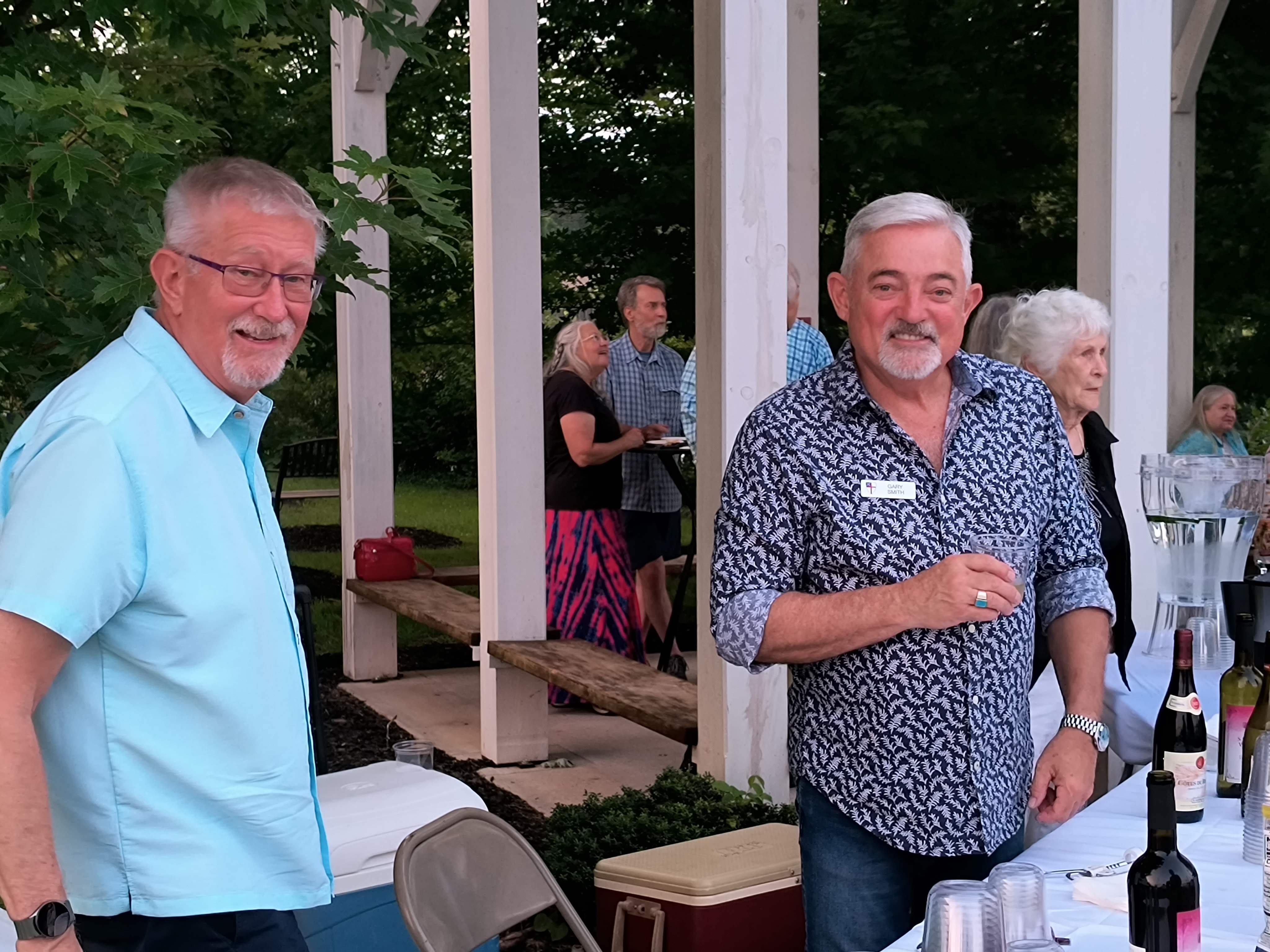 Two gentlemen enjoying conversation at the wine table under the pergola