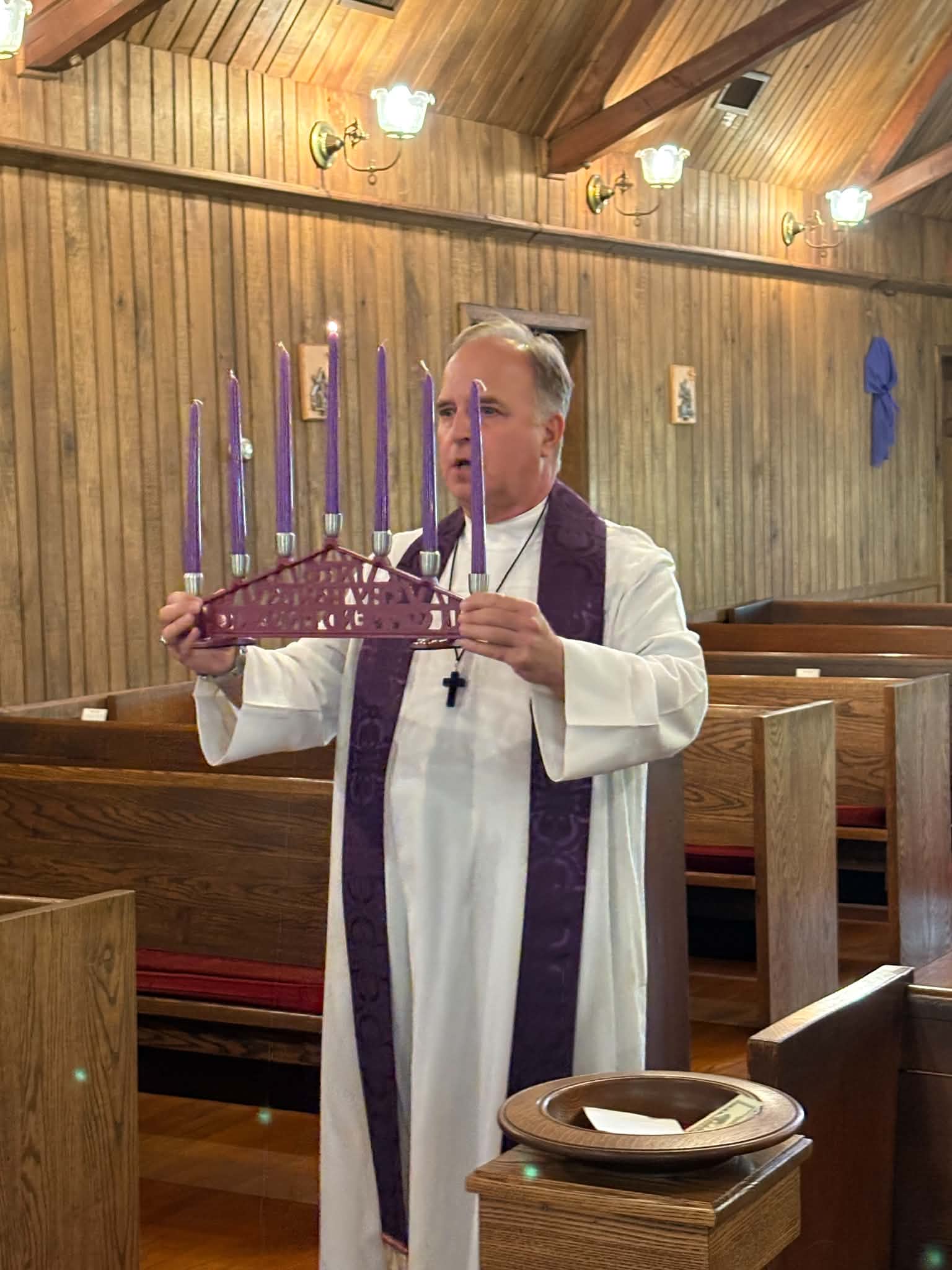 Father Haire holding the Advent candle wreath during worship