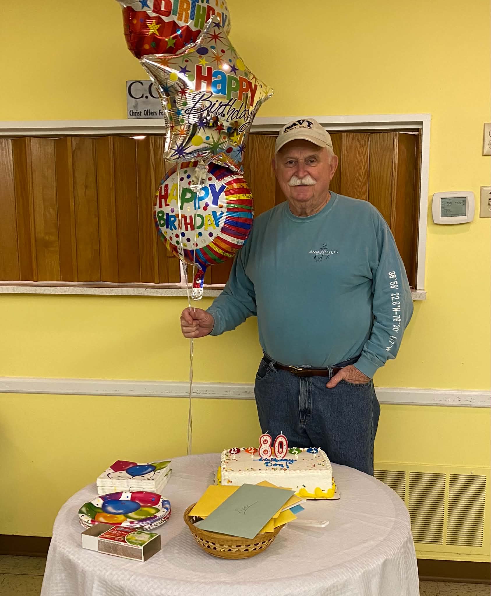 A parishioner celebrating his 80th birthday with cake and balloons