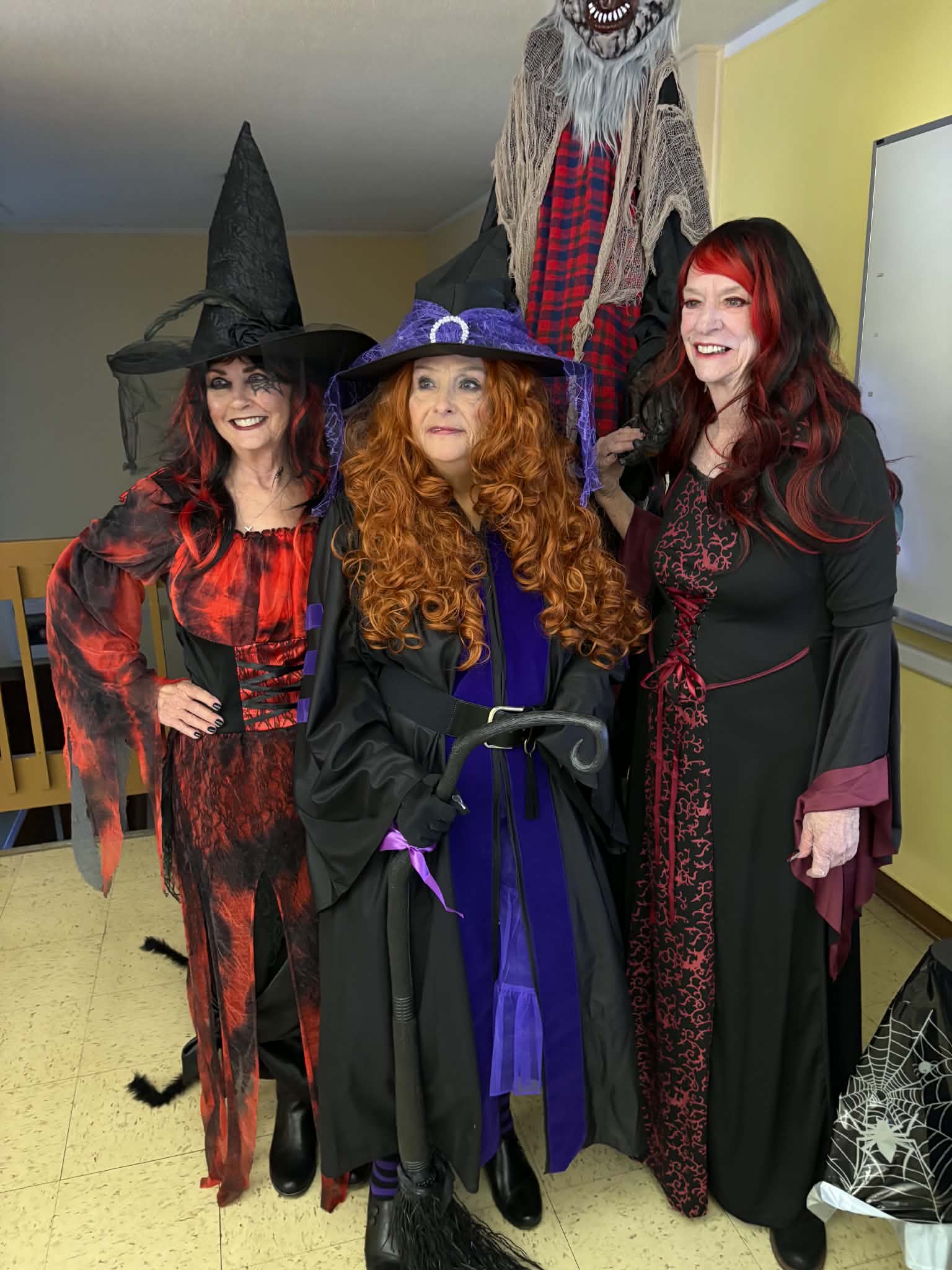 Three members dressed in festive witch costumes for a Halloween gathering