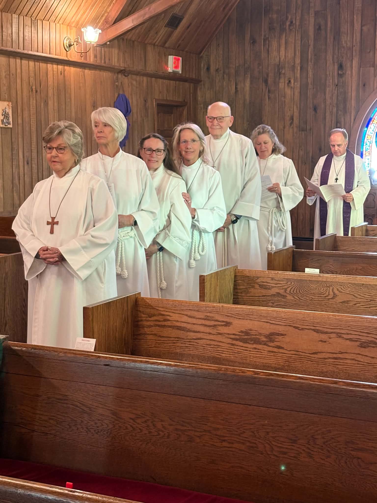 Lay ministers and clergy gathered in white robes for worship