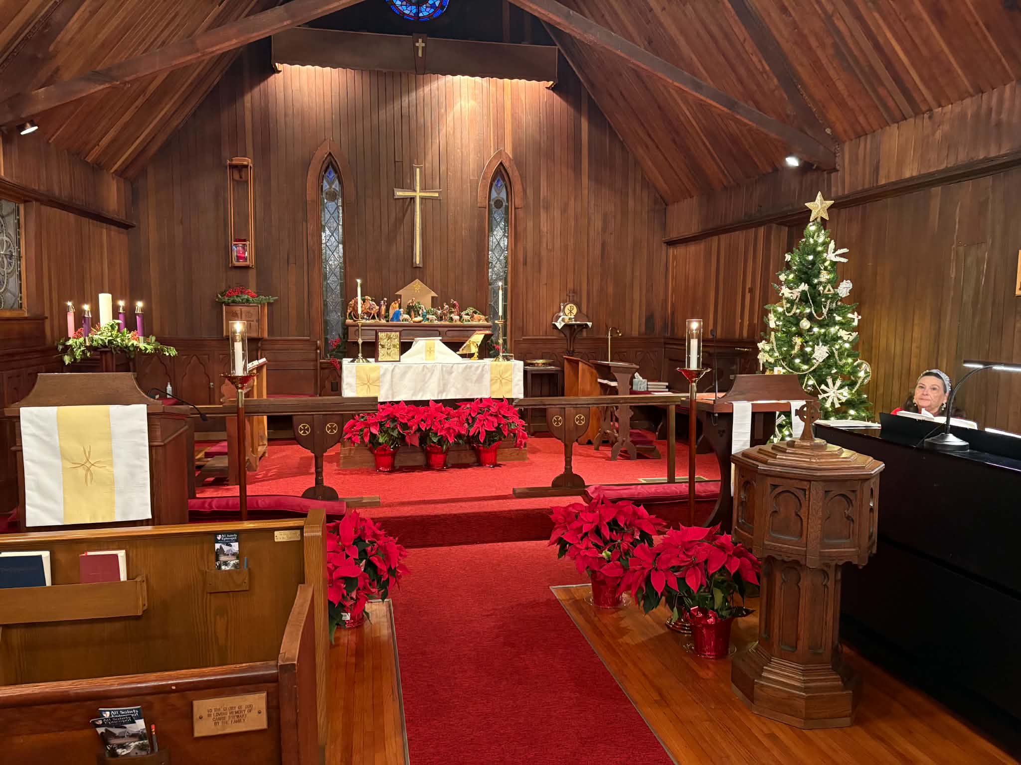 Interior of All Saints Episcopal Church decorated for Advent with poinsettias, a Christmas tree, and the altar